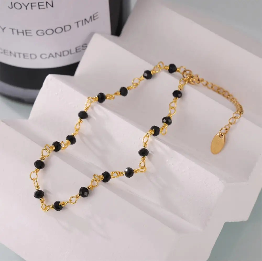 Fotlänk med svarta pärlor och guldfärgad kedja