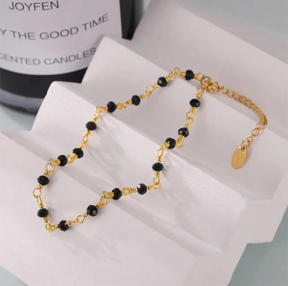 Fotlänk med svarta pärlor och guldfärgad kedja